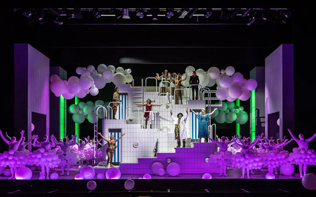 English National Opera stage production of Orpheus in the Underworld with performers amid a bright cloud-like set